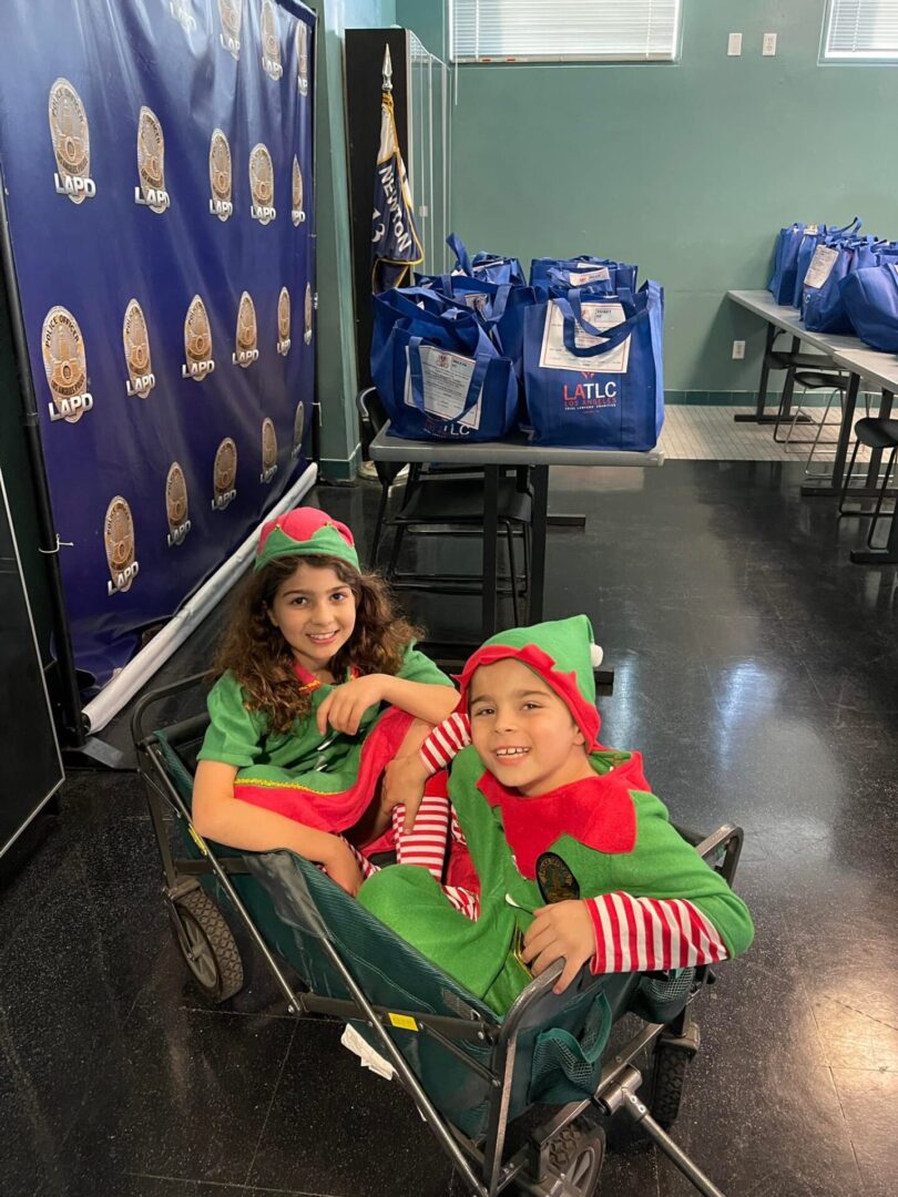 Two children dressed as elves sitting in a cart.