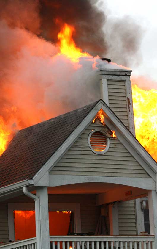 A house that is on fire with smoke coming out of the top.